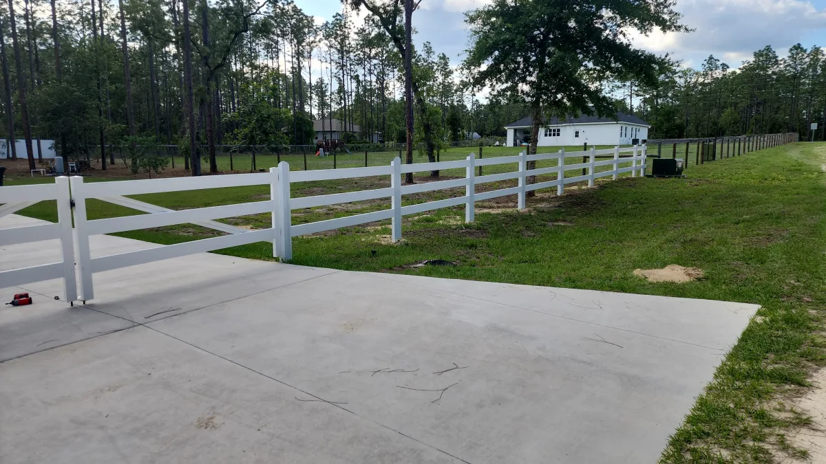White 3-rail vinyl horse fence along driveway entry — Marion County FL