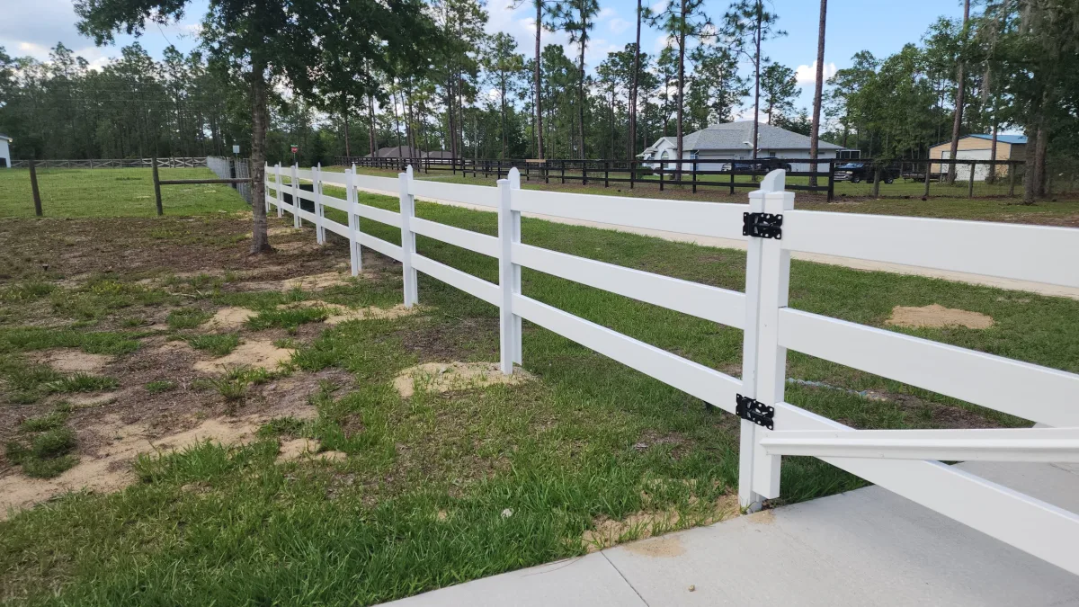 White 3-rail vinyl horse fence long run across pasture — Marion County FL